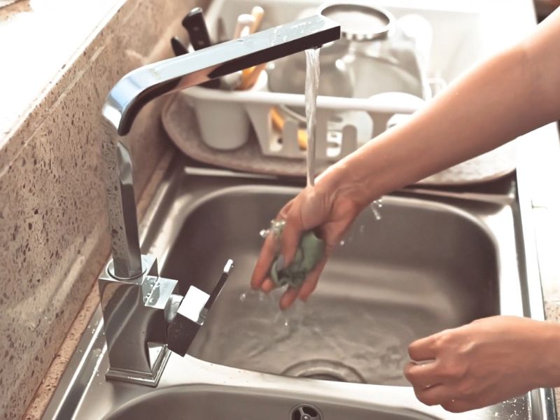 devojka čisti krpu za sudoperu